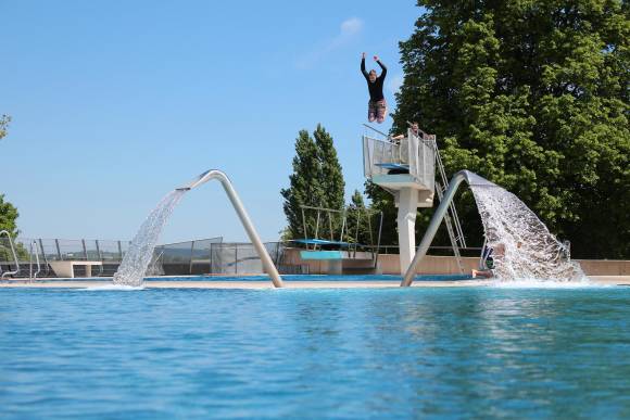 Person springt in Freibad von Sprungturm