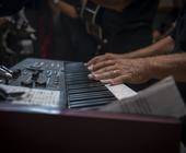 Ein Handpaar auf einem Synthesizer-Keyboard