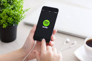 Zwei Hände halten ein Smartphone, das ein Spotify-Logo zeigt 