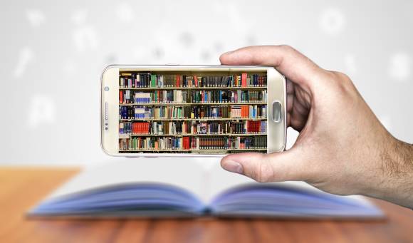 Smartphone mit Büchern auf dem Display über einem Buch 