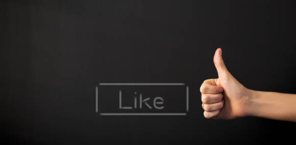 Ein Like-Button und eine Hand mit hochgestrecktem Daumen 