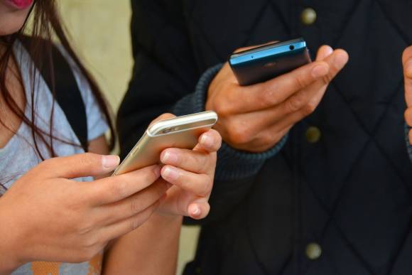 Eine Frau und ein Mann halten ihre Smartphones in der Hand 