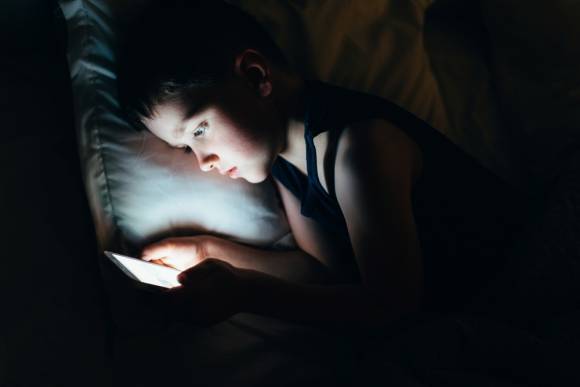 Junge benutzt in der Nacht sein Smartphone 