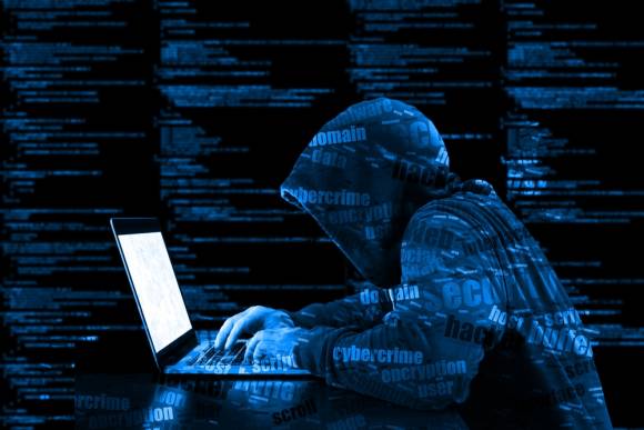Hacker mit Kapuze an einem Notebook 