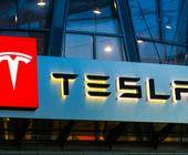 Beleuchtetes Tesla-Logo mit Schriftzug an einem Gebäude