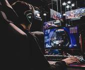 Ein Mann mit Kopfhörern spielt am PC ein Spiel