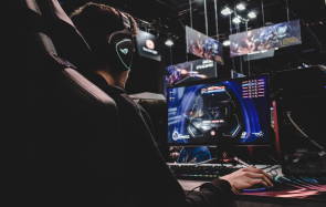 Ein Mann mit Kopfhörern spielt am PC ein Spiel 