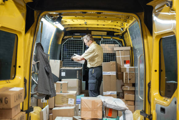 Ein Postangestellter prüft Pakete in einem Postlieferwagen 