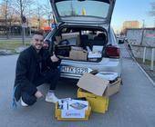 Ein junger Mann freut sich über Kartons voller Computer-Sachspenden