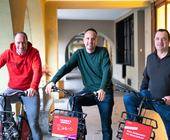 Die drei neuen Besitzer von Publibike sitzen auf einem E-Bike