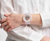 Der Ausschnitt zeigt eine transparente Swatch am Handgelenk einer Frau in einer weissen Bluse