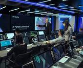 Mehrere Personen arbeiten an Computern in einem Raum, der mit IBM X-Force Command angeschrieben ist