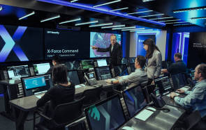 Mehrere Personen arbeiten an Computern in einem Raum, der mit IBM X-Force Command angeschrieben ist 