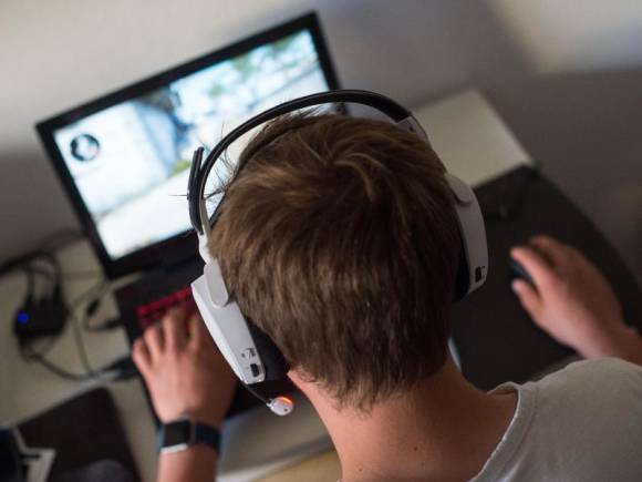 Junger Mann sitzt mit Kopfhörern an einem Notebook 