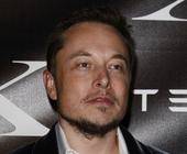 Elon Musk vor einem Tesla-Logo