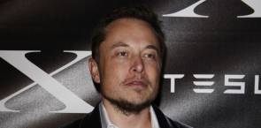 Elon Musk vor einem Tesla-Logo 