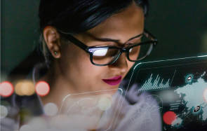 Symbolbild zeigt eine Frau mit Brille und eingeblendeten Grafiken 
