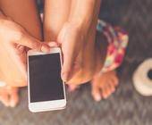 Person mit Smartphone auf Toilette