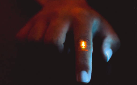 Ein Miniatur-Display auf einem Zeigefinger zeigt einen leuchtenden Tannenbaum 