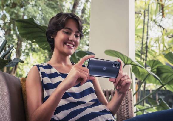 Eine Frau hält lachend ein Motorola Moto G82 