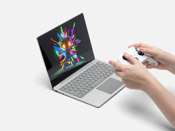 Jemand hält einen Xbox-Game-Controller vor einem Surface Laptop 