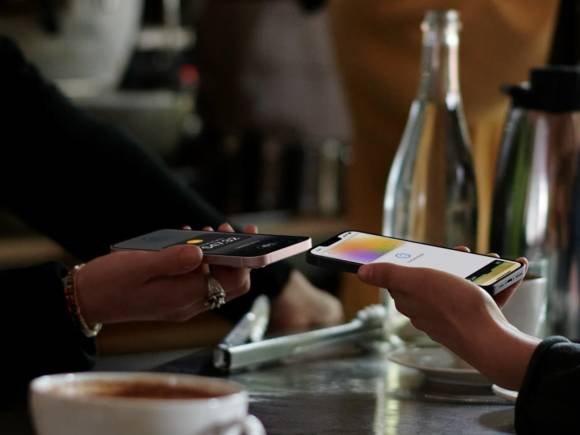 Das Foto zeigt zwei Personen mit iPhones, die eine Zahlung auslösen