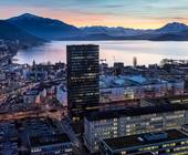 Gebäude in Zug, Dämmerungslicht, im Hintergrund sind der Zugersee und die Alpen