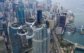 Drei Quadcopter-Drohnen schweben über einer Grossstadt mit Wolkenkratzern 