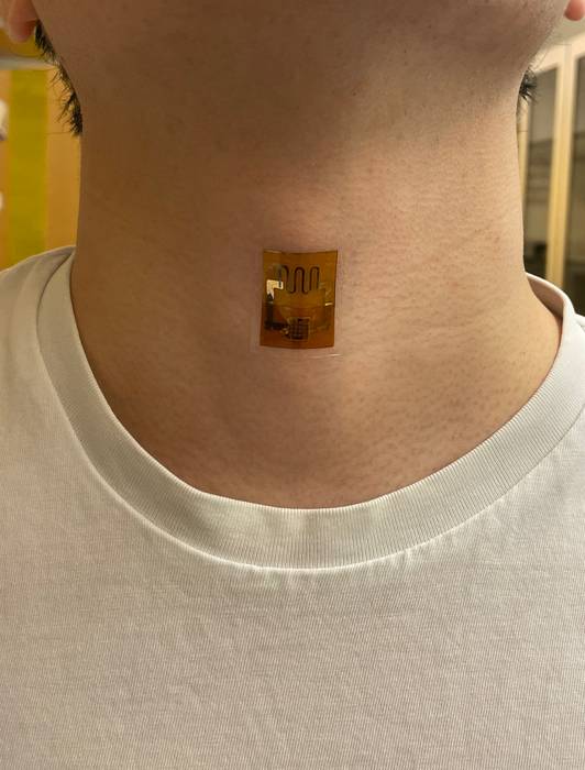 Ein Biofilm-Aufkleber mit Leiterbahnen am Hals eines Probanden 