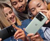 Drei lachende junge Menschen mit One-Plus-Smartphones