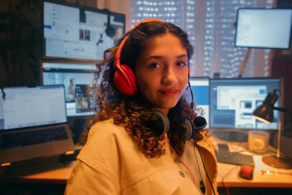 Eine junge Frau mit Headset an einem Schreibtisch mit mehreren Bildschirmen 