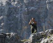 Ein Wanderer steht auf einem Felsen und knipst mit dem Smartphone ein Bild