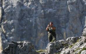Ein Wanderer steht auf einem Felsen und knipst mit dem Smartphone ein Bild 