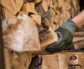 Eine Hand greift nach einem Holzscheit in einem Holzstapel