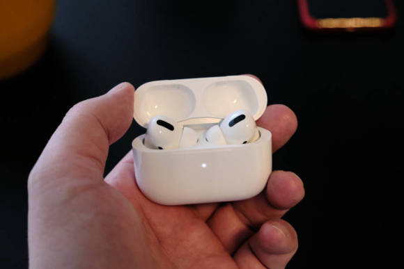 Jemand hält in der Hand die Airpods Pro, die in ihrem geöffneten Case stecken 