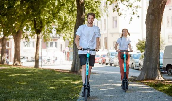 Ein junger Mann und eine junge Frau auf Scootern der Marke Tier 