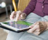 Eine Seniorin spielt auf einem Tablet Solitaire