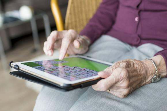 Eine Seniorin spielt auf einem Tablet Solitaire 