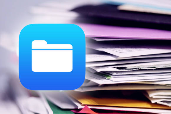 Das Papier muss endlich weg! Im Hintergrund ist ein ungeordneter Papierstapel zu sehen, im Vordergrund das Symbol der «Dateien»-App