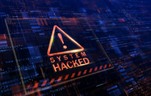 Symbolbild zeigt Schrift "System Hacked" auf einem Display mit Programmcode 