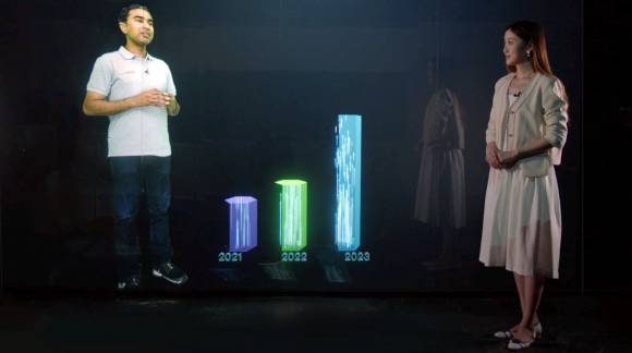 Ein Mann steht während seiner Telepräsenz-Präsentation neben einem 3D-Säulendiagramm