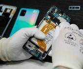 Person mit Anti-Statik-Handschuhen arbeitet mit einem kleinen Werkzeug an einem geöffneten Smartphone