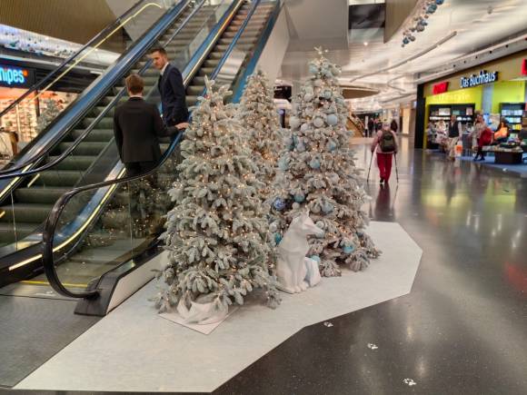 Künstliche weiss beschneite Weihnachtsbäume neben einer Rolltreppe im Sihlcity