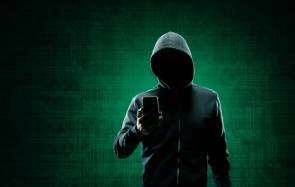 Krimineller mit Hoodie und einem Smartphone 