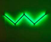 Grün leuchtende Nanoleaf-Elemente an einer Wand formen ein W