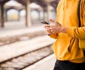 Symbolbild zeigt einen Mann am Bahngleis mit Smartphone in der Hand