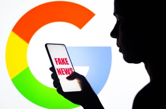 Symbolbild zeigt Silhoutte einer Person mit Smartphone, auf welchem "Fake News" steht 