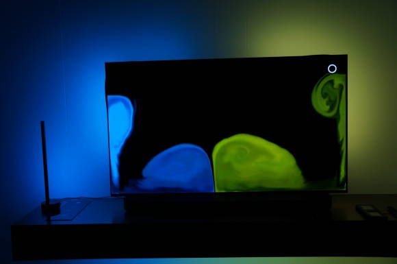 Smart-TV zeigt blaue und gelbe Formen, während die Beleuchtung um das Gerät der Farbgebung folgt