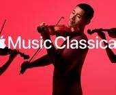 Drei Personen spielen Geige vor rotem Hintergrund, darüber das Apple-Logo und der Text 