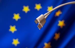 Symbolbild zeigt einen Lightning- und einen USB-C-Stecker vor einer Europa-Flagge 